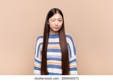 Asian Young Woman Looking Happy And Friendly, Smiling And Winking An Eye At You With A Positive Attitude