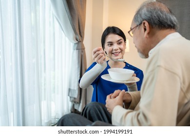 Asian young woman nurse at nursing home taking care of disabled senior elderly man on wheelchair. Beautiful Therapist doctor feeding food to older patient in house. Medical insurance service concept. - Powered by Shutterstock