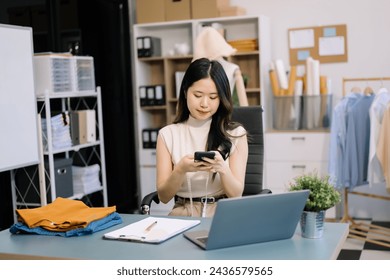  Asian young woman on desk of fashion designer and holds tablet, laptop and smartphone in studio
 - Powered by Shutterstock