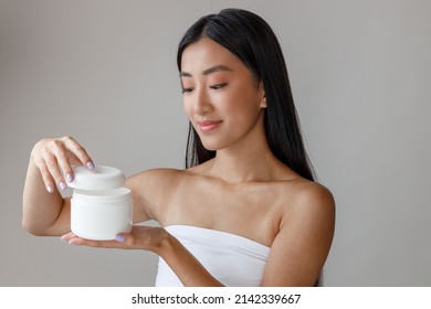 Asian Young Woman Opening Jar Of Cosmetic Cream