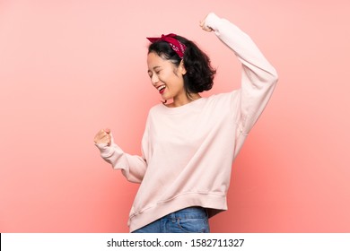 Asian young woman over isolated pink background celebrating a victory