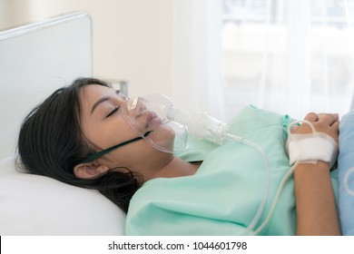 Asian young woman patient receiving oxygen mask lying on a hospital bed. - Powered by Shutterstock