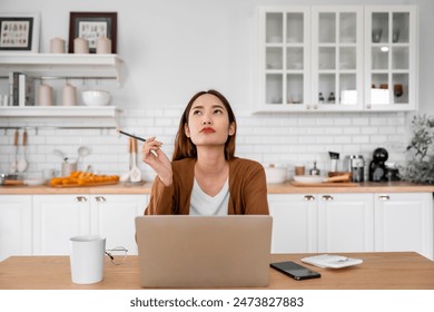 Asian young woman seriously working on computer laptop in house. She thinking find solution problem of work - Powered by Shutterstock