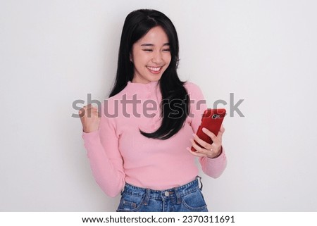 Asian young woman showing excited when looking to mobile phone that she hold