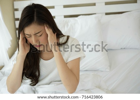 Asian young woman sitting on bed is headache after wake up in the morning.