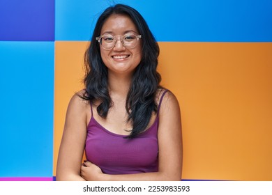 Asian young woman standing over colorful background looking positive and happy standing and smiling with a confident smile showing teeth  - Shutterstock ID 2253983593
