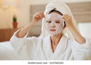 Asian young woman taking off sheet mask that immediately diminishing signs of agning - Shutterstock ID 2137465245