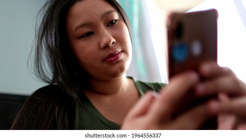 Asian Young Woman Using Cellphone Device. Japanese Descent Person Looking At Smartphone