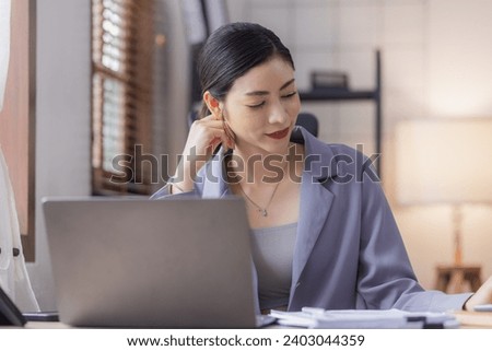 Asian young woman using laptop working with financial documents at home office, Woman online working concept.