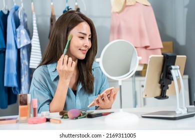 Asian Young Woman Vlogger Talk To Camera To Review The Cosmetic At Home. Attractive Beautiful Beauty Blogger Influencer Live Streaming And Showing Makeup Brush To Followers And Smile In Office Store.