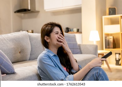 asian young woman is watching tv and sitting on the floor in living room at home
