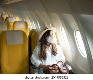 Asian Young Woman Wearing Face Mask Is Traveling On Airplane , New Normal Travel After Covid-19 Pandemic Concept.