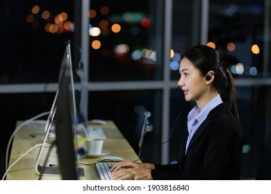 Asian Young Woman Wearing Headphone Headset Working Overtime Late At Night In Call Center Office. Concept For Business At Night.