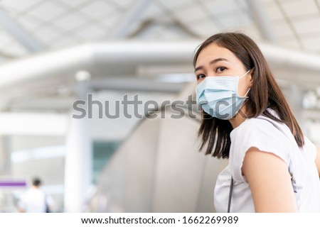 Asian young woman wearing a hygiene protective mask over her face while walking at the crowded shopping mall. Healthcare and sickness prevention from coronavirus, Covid-19 influenza in crowded place.