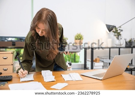 Asian young woman working with financial data calculator with tablet computer and writing make note calculate, female calculating budget financial and accounting, Social distancing working from home