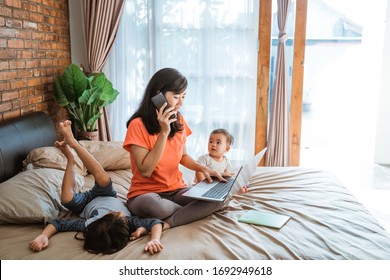 asian young woman working while taking care of her children at home