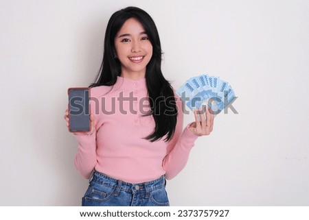 Asian young women smiling while holding money and showing blank mobile phone screen