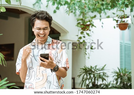 Asian youth holding and looking at cellphones are very happy when walking around