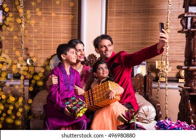 Asian/Indian Young Family Taking Selfie Or Self Photograph At Home With Gift Boxes On Diwali Festival Night.