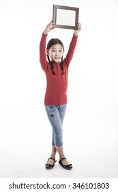 A Asian(korean, Japanese, Chinese) Girl(kid, Student, Child, Woman, Female) Wearing Red Shirts And Denim Pants Stand Up With A Wood Photo Frame For Friend And Family Isolated White.