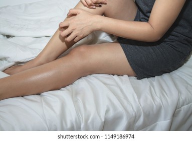 Asians Have Itchy Legs.women Itching At Thighs.Asian Girl Wearing Gray Dress Itching In The Legs.The Woman Was Scratching Her Leg.In A White Bedroom With Sunlight.