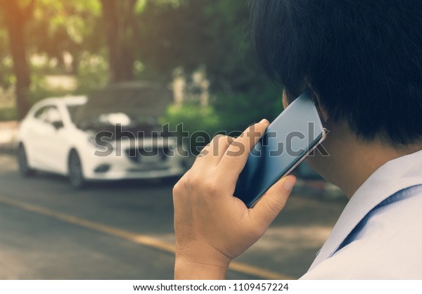 Asians use smart phone  call after a mechanic\
because car broken down on a hot\
day.\
