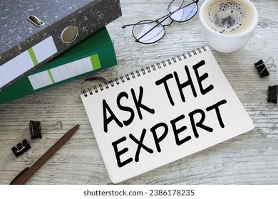ASK THE EXPERTS a cup of coffee. glasses. two office folder gray notepad. text on the page