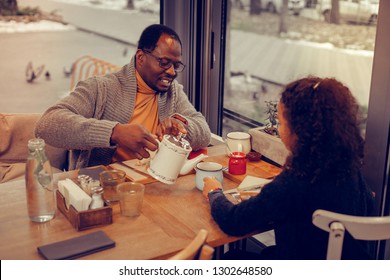 Asking for tea. Curly dark-haired daughter asking for more tea while having breakfast with father - Powered by Shutterstock