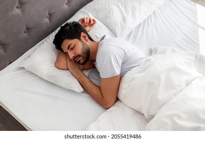 Asleep young arab man sleeping, resting peacefully in comfortable bed, lying with closed eyes, free space. Recreation, deep male sleep, time to rest and nap concept - Shutterstock ID 2055419486