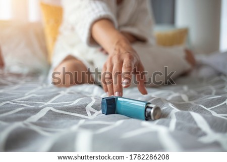 Asmathic girl catching inhaler having an asthma attack. Young woman having asthma attack. She is holding inhaler. Asthmatic woman using an asthma inhaler during asthma attacks 
