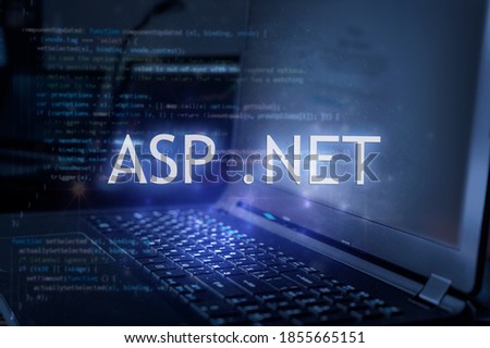ASP .NET inscription against laptop and code background. Learn dot net programming language, computer courses, training. 