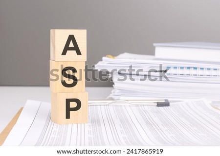 ASP text on wood blocks on a document with tables on a stack of documents in the gray background