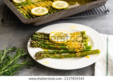 Asparagus baked with sliced lemon, fresh rosemary, butter, and cheese. Fresh baked delicious meal close up on a plate