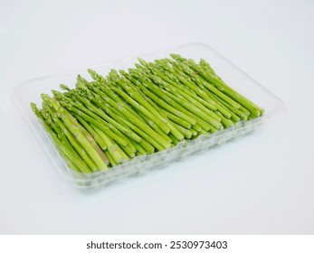 Asparagus is cut into pieces in a plastic container on a white background. It is an organic and healthy vegetable. - Powered by Shutterstock