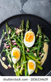 Asparagus with eggs and french dressing with dijon mustard, onion chopped in red vinegar taragon on grey textured background, top view.