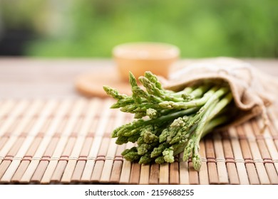 Asparagus is green and straight vegetable. Fresh, green asparagus is crispy for cook on wood table with salt