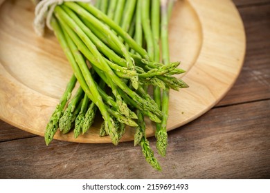 Asparagus is green and straight vegetable. Fresh, green asparagus is crispy for cook on wood table with salt