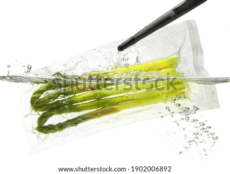 Asparagus for sous vide cooking, taking out or putting into the water; isolated on white background