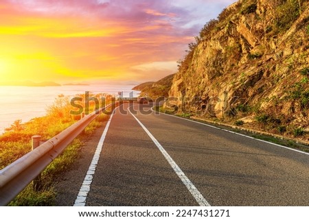 Asphalt highway and mountain scenery at sunset by the seaside