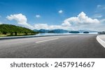 Asphalt highway road and lake with mountains nature landscape on a sunny day. Beautiful coastline in summer season.