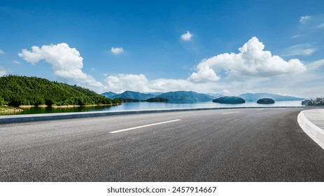 Asphalt highway road and lake with mountains nature landscape on a sunny day. Beautiful coastline in summer season. - Powered by Shutterstock