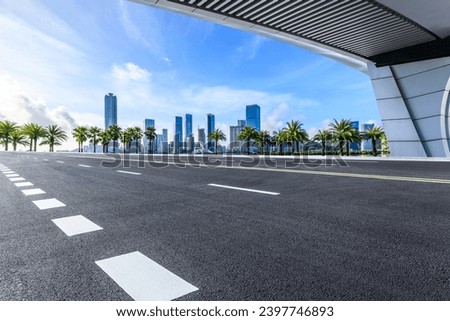 Asphalt highway road and pedestrian bridge with city skyline under blue sky