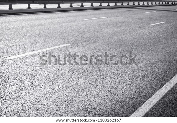 Asphalt on wide highway. Black and white image,\
selective focus