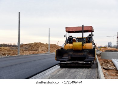 Asphalt paver machine during road work. Road Machinery at construction site for paving works. Screeding the sand for road concreting. Asphalt pavement is layered over concrete pavement. Road Surfacing