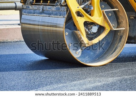 The asphalt paver, a vibrating roller, presses the new hot asphalt onto the roadway. Road repair.