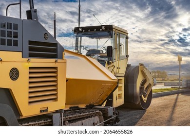 Asphalt paving equipment. Asphalt paver and heavy vibratory roller. Construction of new roads and road junctions. Heavy construction industrial machinery - Shutterstock ID 2064655826