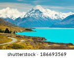 asphalt road along Lake Pukaki view from Glentanner Park Centre near Mount Cook; on a background of blue sky with clouds; snowy Southern Alps.