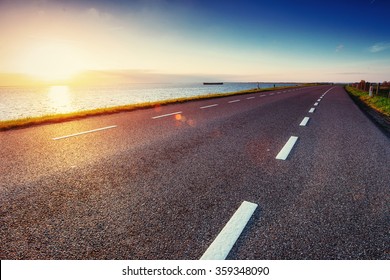 Asphalt Road Along The Sea At Sunset.