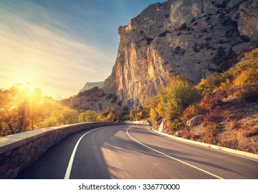 Asphalt road in autumn forest at sunrise. Crimean mountains.