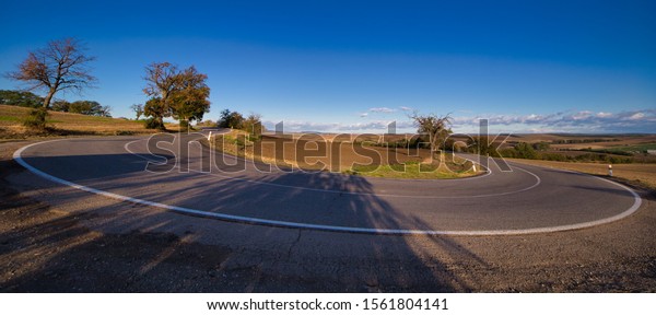 Asphalt road with bends between fields and trees\
at sunrise, South Moravia,\
Czechia